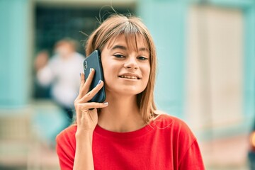 Caucasian teenager girl smiling happy talking on the smartphone at the city.