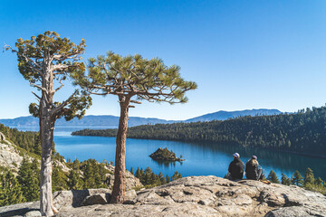 Two people sit on rock overlooking Emerald Bay, Lake Tahoe, California