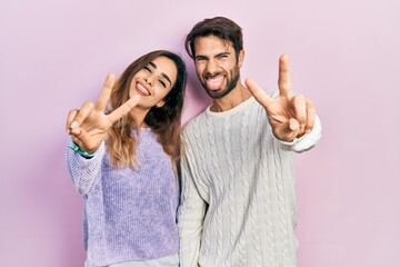 Young hispanic couple wearing casual clothes smiling with tongue out showing fingers of both hands...