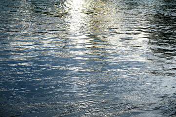 Sun reflection on water surface. Disturbed river surface at sunset.  
