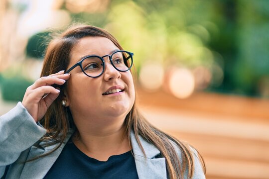 Young hispanic plus size businesswoman smiling happy standing at the city.