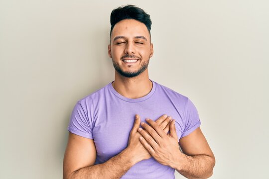 Young arab man wearing casual clothes smiling with hands on chest, eyes closed with grateful gesture on face. health concept.