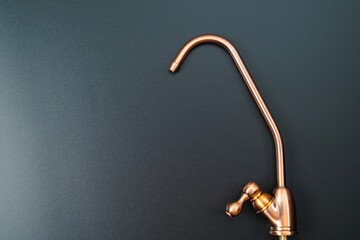 Brass tap to filter drinking water on a black background.