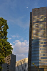 Fototapeta premium ビルの間に輝く夕陽と月