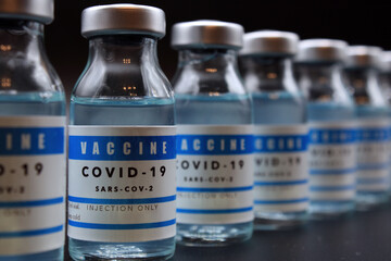 Covid-19 vaccine vials lined up on a black background