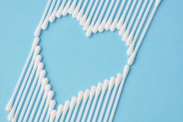 cotton buds arranged in heart shape on blue background