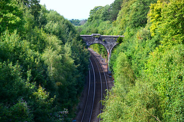 Stone bridge over the railway surrounded by green forest in Scotland, Wales. Romantic stone bridge over railway in beautiful forest, UK. 