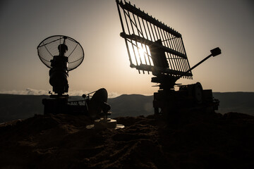 Space radar antenna on sunset. Silhouettes of satellite dishes or radio antennas against night sky....