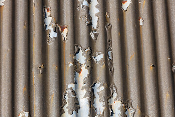 Photograph of brown paint peeling off a corrugated iron roof