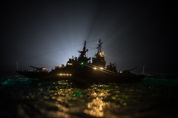 Fototapeta premium Silhouettes of a crowd standing at blurred military war ship on foggy background. Selective focus.