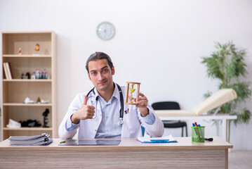 Young male doctor in time management concept