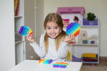 children's popular pop it toy, baby girl holding anti-stress toy in her hands