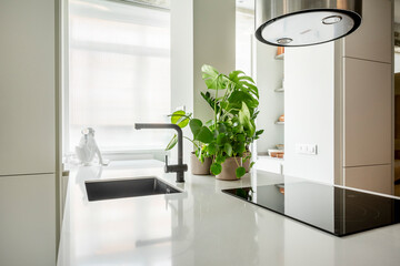 Image of a white kitchen countertop with a black ceramic hob and sink
