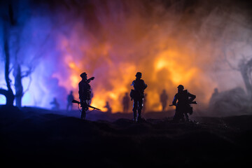 Naklejka na ściany i meble War Concept. Military silhouettes fighting scene on war fog sky background, World War Soldiers Silhouette Below Cloudy Skyline At night. Battle in ruined city. Selective focus