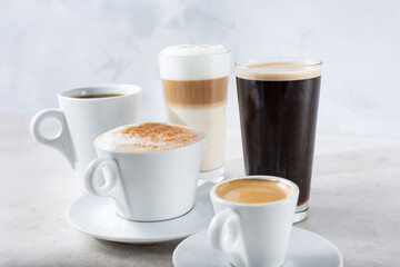 A view of a collection of popular coffee drinks in cups and glasses.