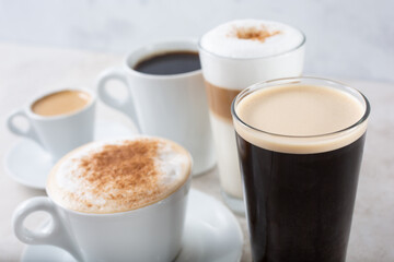 A view of a collection of popular coffee drinks in cups and glasses.