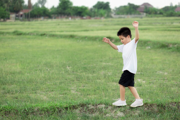 happy little Asian boy run on the field