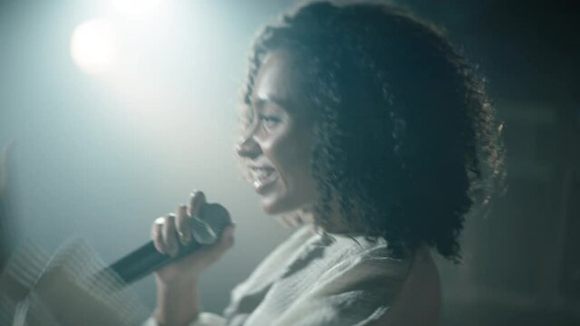 CU Portrait of Black African American young female comedian performing her stand-up monologue on a stage of a small venue. Shot with ARRI Alexa Mini LF with 2x anamorphic lens