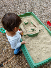 little child playing in a sandbox