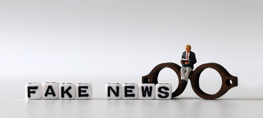 White dice and 'FAKE NEWS' with News, solution and business concepts on white background. White cube and miniature people.
