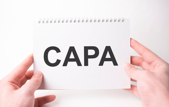 capa word inscription on white card paper sheet in hands of a man. Black letters on white paper. Business concept.