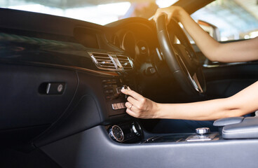 Hands woman driver turning on car air condition system,Button on dashboard in modern car panel,Auto...