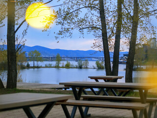 Fototapeta premium Empty street cafe against the background of the city, river, bridge and mountains.