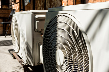 A pair of Split Type Inverter Air conditioner condensers outside a cafe or restaurant. HVAC for...