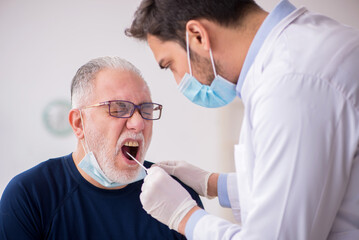Fototapeta premium Old male patient visiting young male doctor otorhinolaryngologis