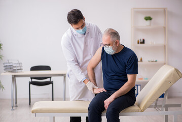 Obraz premium Old male patient visiting young male doctor in vaccination conce