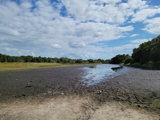 Dried river bank with scattered white clouds