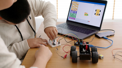 Young asia student remotely learn online at home with parent in coding robot car and electronic...