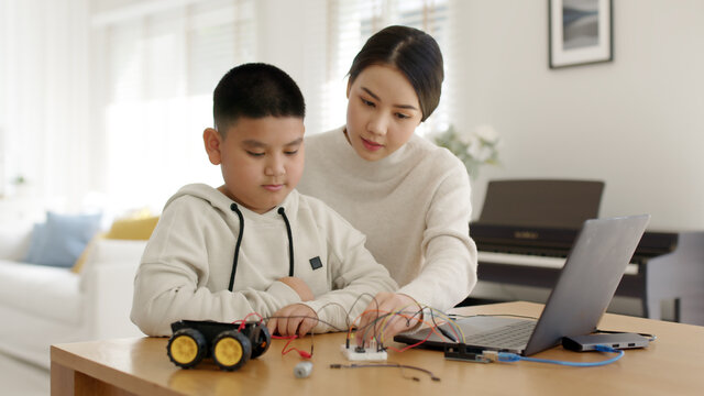 Young asia student remotely learn online at home with parent in coding robot car and electronic board cable in STEM, STEAM, mathematics engineer science technology computer code in robotics for kids.