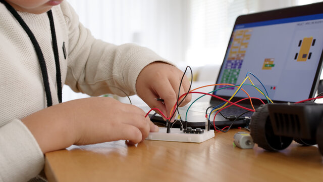 Young Asia Student Remotely Learn Online At Home In Coding Robot Car And Electronic Board Cable In STEM, STEAM, Mathematics Engineering Science Technology Computer Code In Robotics For Kids Concept.