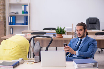 Young male employee looking after new born at workplace