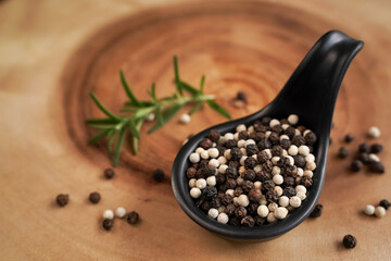 White and black pepper in spoon and with black background, industrial concept