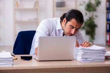 Young businessman employee unhappy with excessive work in the of