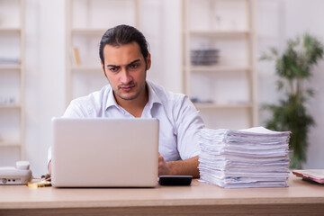 Fototapeta premium Young businessman employee unhappy with excessive work in the office
