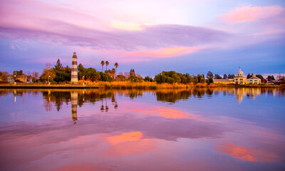 Fototapeta na wymiar lighthouse at sunset, blue pink magnificent nature sky reflection on the water