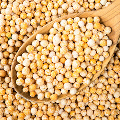dried whole yellow peas in wooden spoon closeup