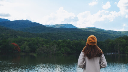 Rear view image of a woman looking at a beautiful greenery mountains by the lake