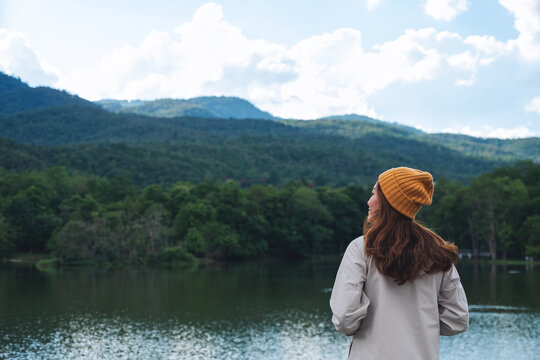 Rear view image of a woman looking at a beautiful greenery mountains by the lake