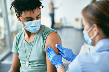 Young African American man receiving coronavirus vaccine at vaccination center.