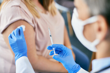 Close-up of doctor vaccinating patient against coronavirus at medical clinic.