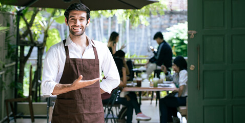 Handsome waitress holding business show hand sign  'Welcome' in Coffee cafe shop or Restaurant door. Small businesses and real estate