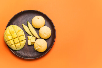Plate with tasty mango ice cream on color background