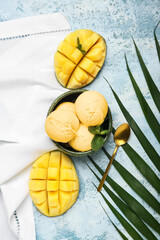 Bowl with tasty mango ice cream and palm leaf on color background