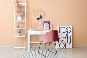 Stylish workplace with laptop and organizers near color wall