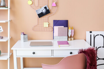 Stylish workplace with laptop and organizers near color wall