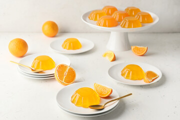 Plates with tasty orange jelly on white background